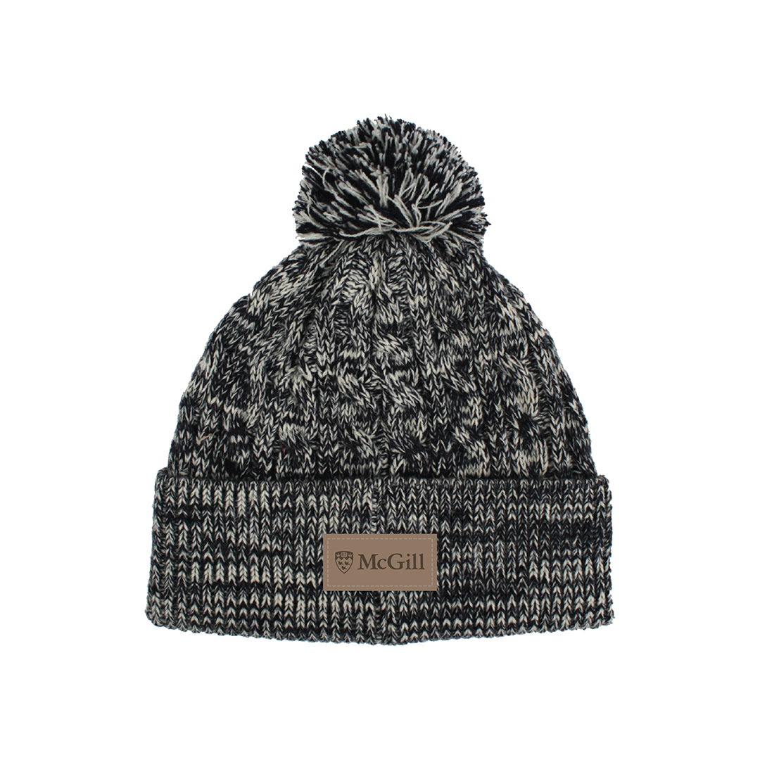 UNISEX - Welcome the cold in style with this soft, cable knit tuque topped with a fluffy pom-pom. Features a faux suede open edged patch with the McGill logo.