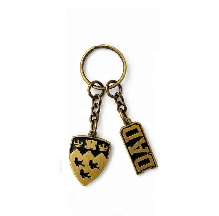 Antique gold tone McGill Dad keychain with embossed crest and “Dad” lettering on chain hardware