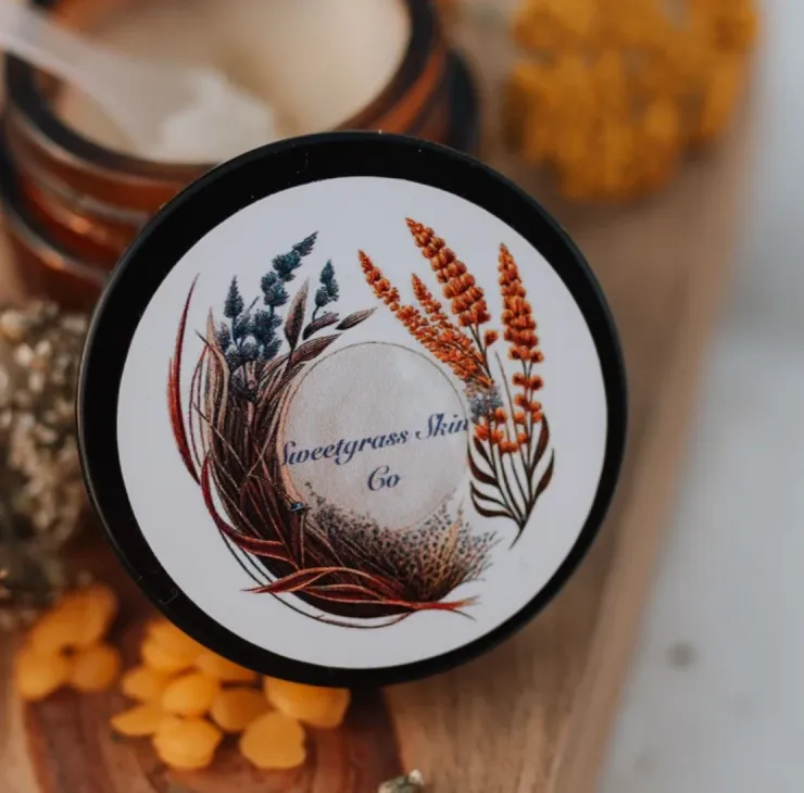 Gatherer Balm moisturizer in amber glass jar with botanical label, shown open with cream balm and applicator scoop.