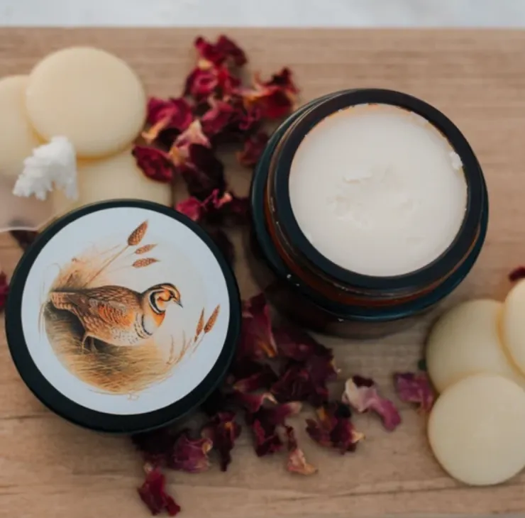 Prairie Cream moisturizer in amber glass jar with prairie bird illustration, shown open with cream balm and botanical accents.